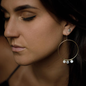 
                  
                    The Shatki Hoops consist of silver dot charms hanging from a gold hoop earring paired with silver dot studs for a feminine multi-piercing look. 
                  
                