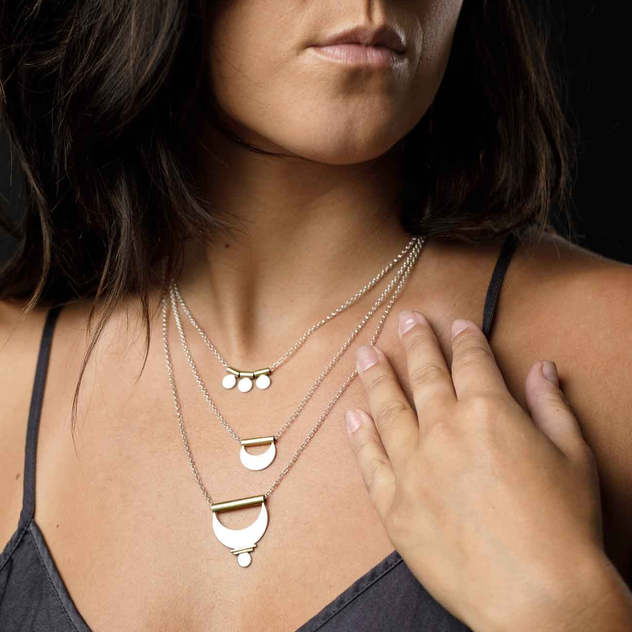 A necklace with three silver dot charms layered with a crescent moon necklace layered with the Large Prana Pendant for the ultimate feminine look.