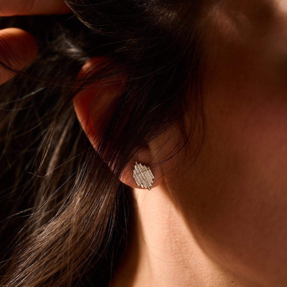 
                      
                        Close-up of an ear with a diamond earring, hair partially covering the face.
                      
                    