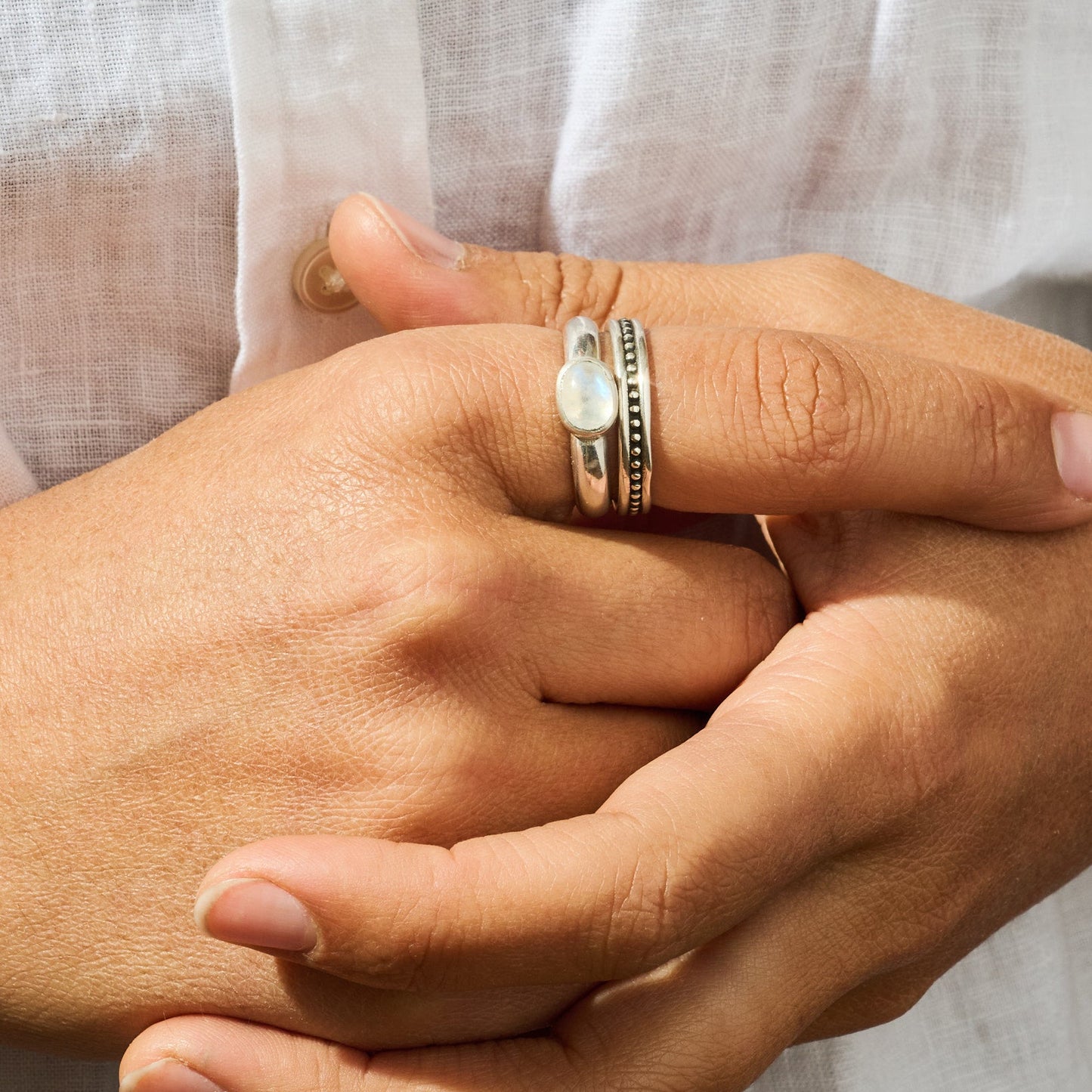 Close-up of hands with rings on a neutral background