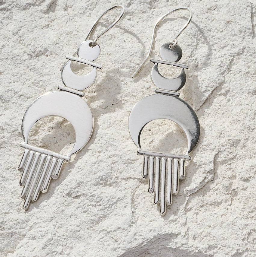 
                      
                        Set of silver and gold earrings on a textured white surface
                      
                    