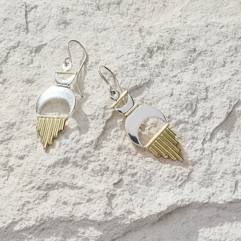 
                      
                        Set of silver and gold earrings on a textured white surface
                      
                    