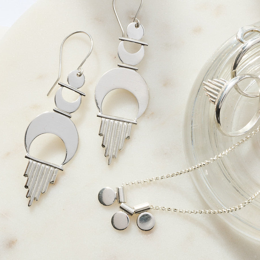 
                      
                        Silver jewelry including necklaces and earrings on a neutral background
                      
                    
