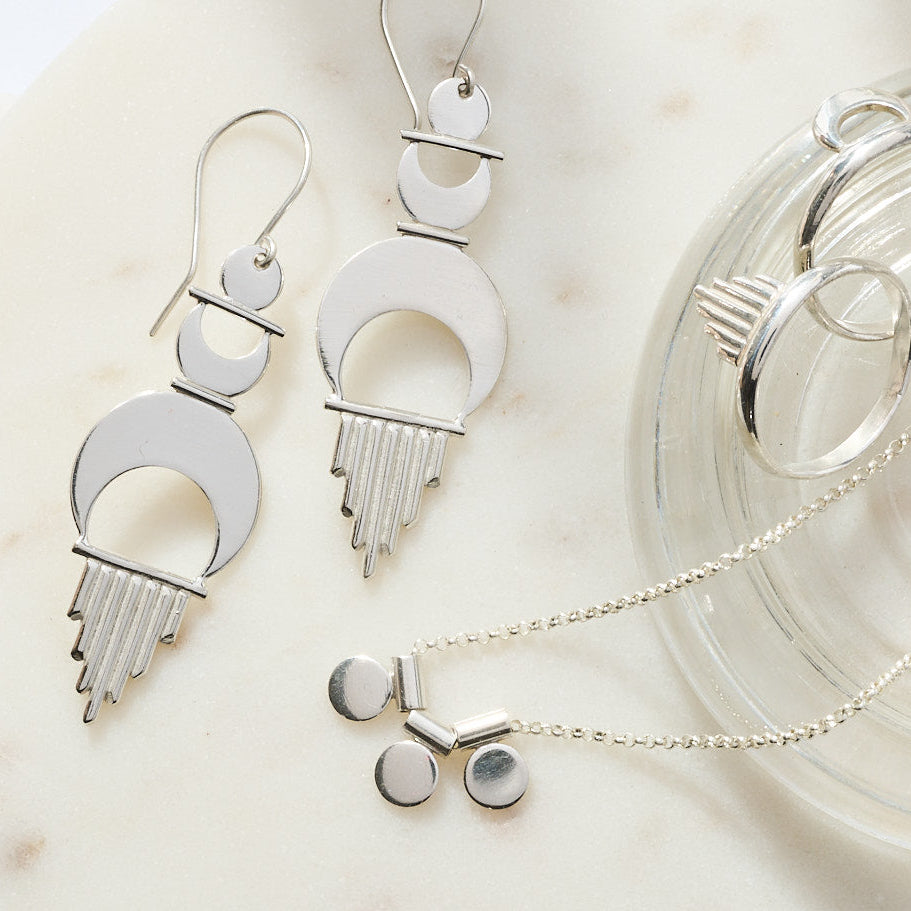 
                      
                        Silver jewelry including necklaces and earrings on a neutral background
                      
                    