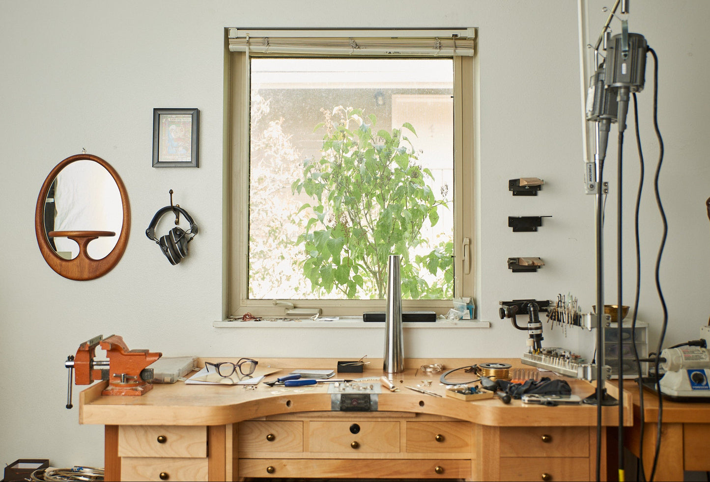 Wooden workbench with tools and equipment in a room with a window and shelves.