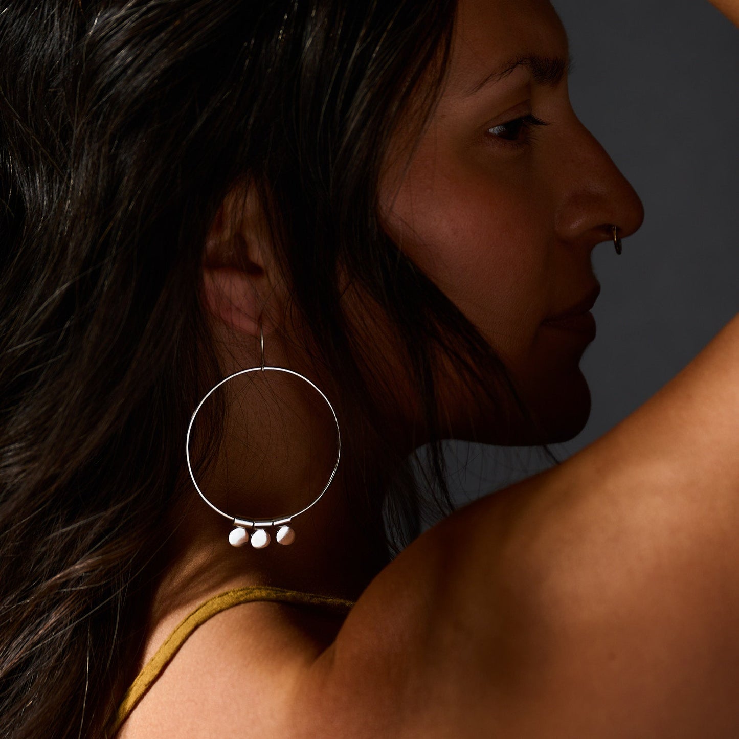 Close-up of a woman with hoop earrings against a dark background