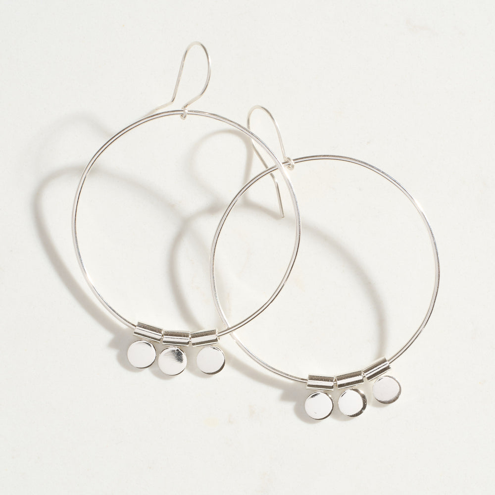 Silver hoop earrings with small round pendants on a white background
