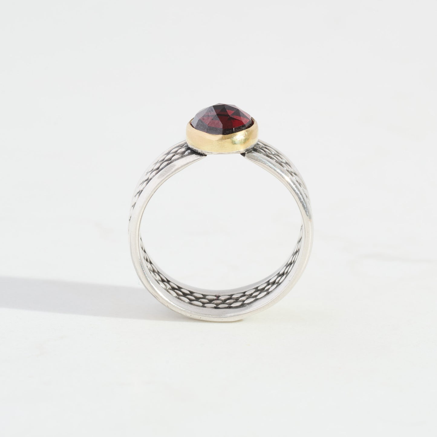 Ring with a red gemstone and silver band on a white background