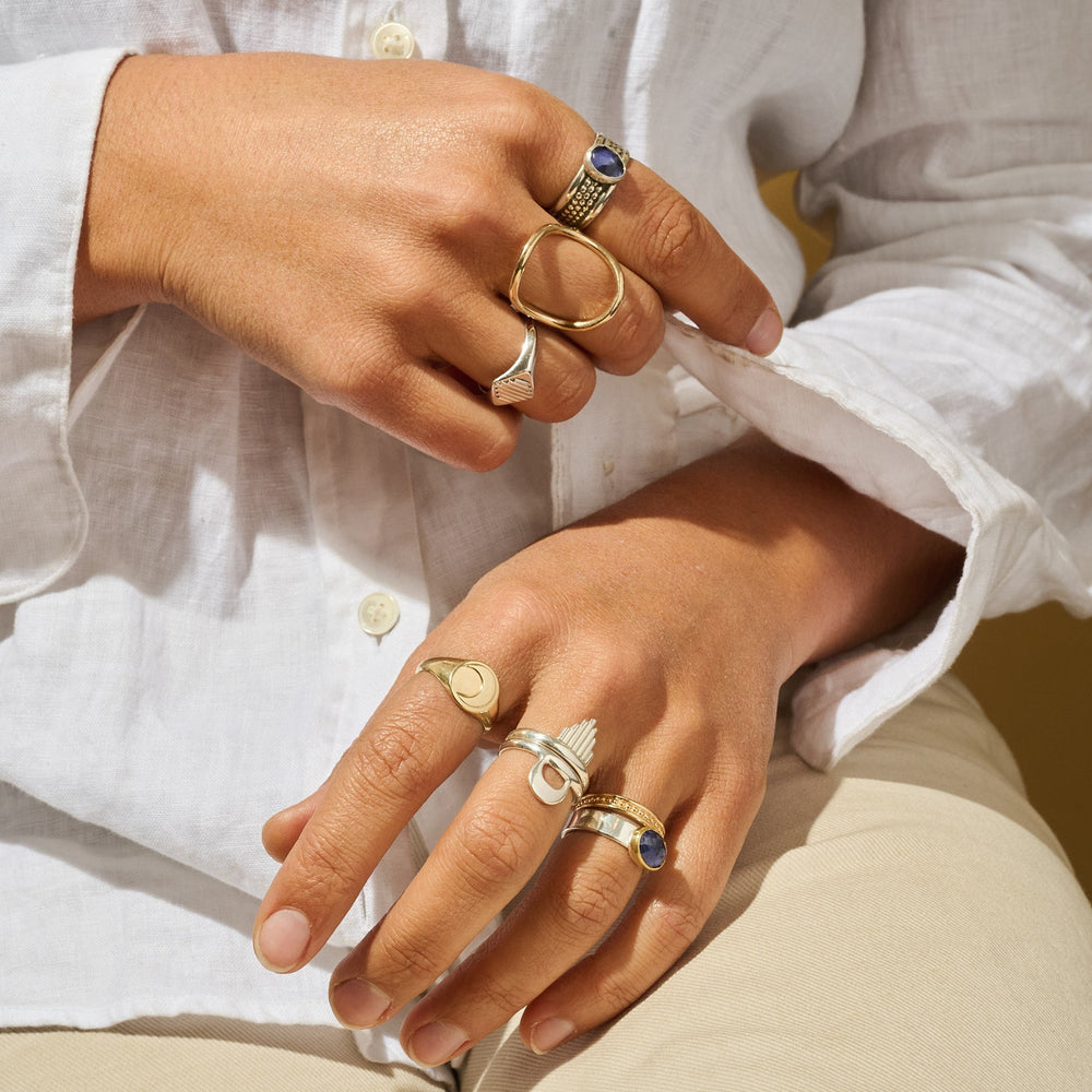 
                      
                        Close-up of hands wearing multiple rings with a white shirt background
                      
                    