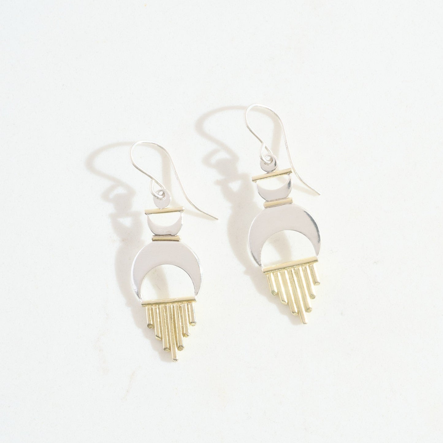 Pair of earrings with gold sun rays intermixed with silver crescent moons on a white background